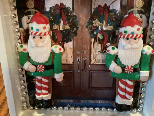 Double front doors with green and red wreaths, silver trim, and festive nutcrackers on both side of doors