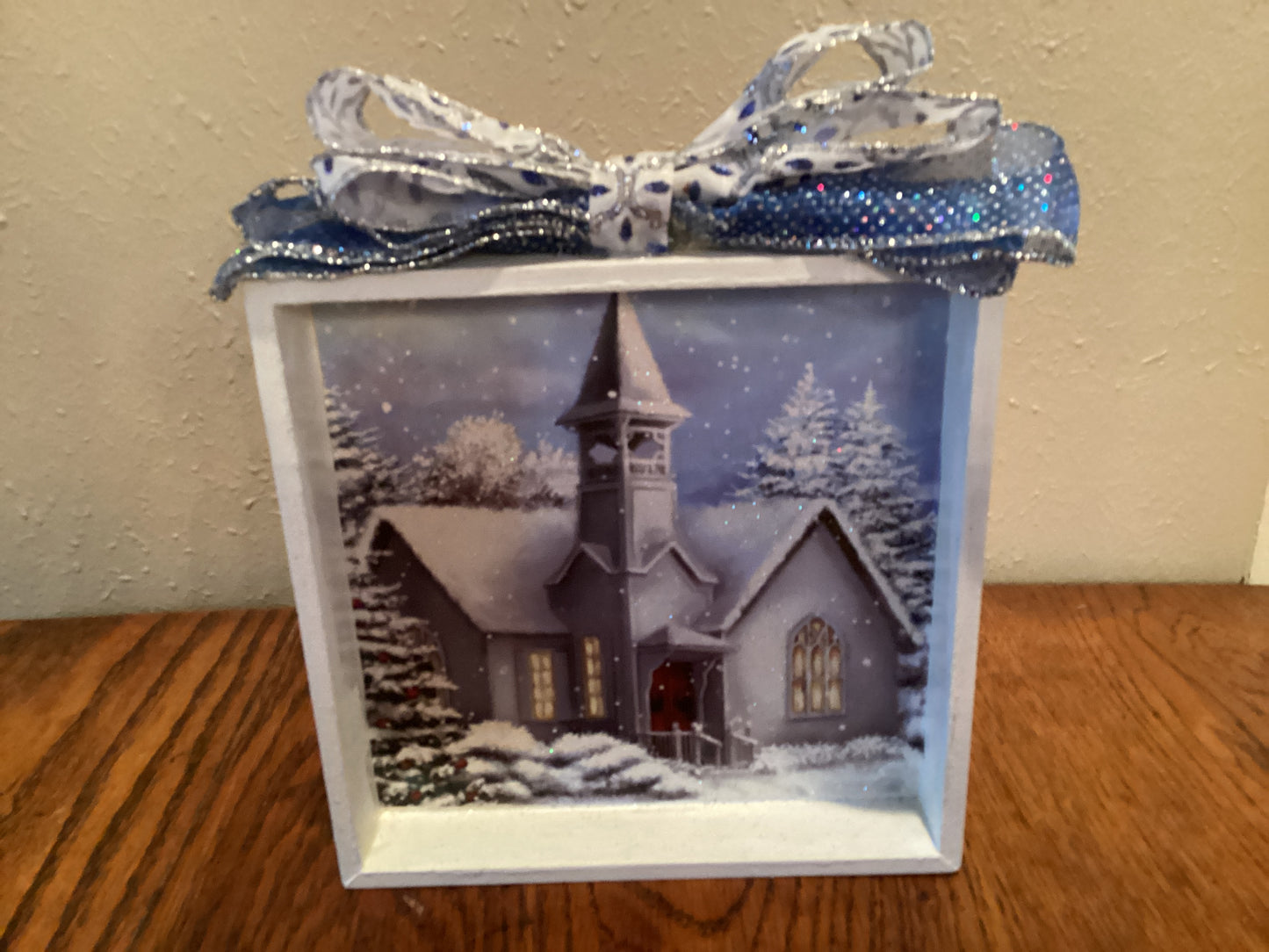 7" X 7" white box with snow-covered church and trees next to a Christmas tree on blue background