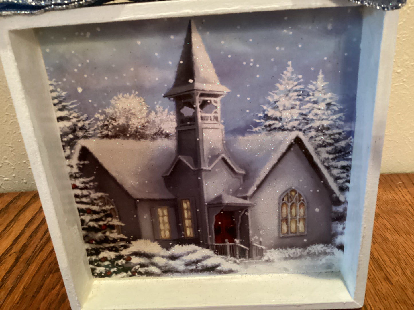 7" X 7" white box with snow-covered church and trees next to a Christmas tree on blue background