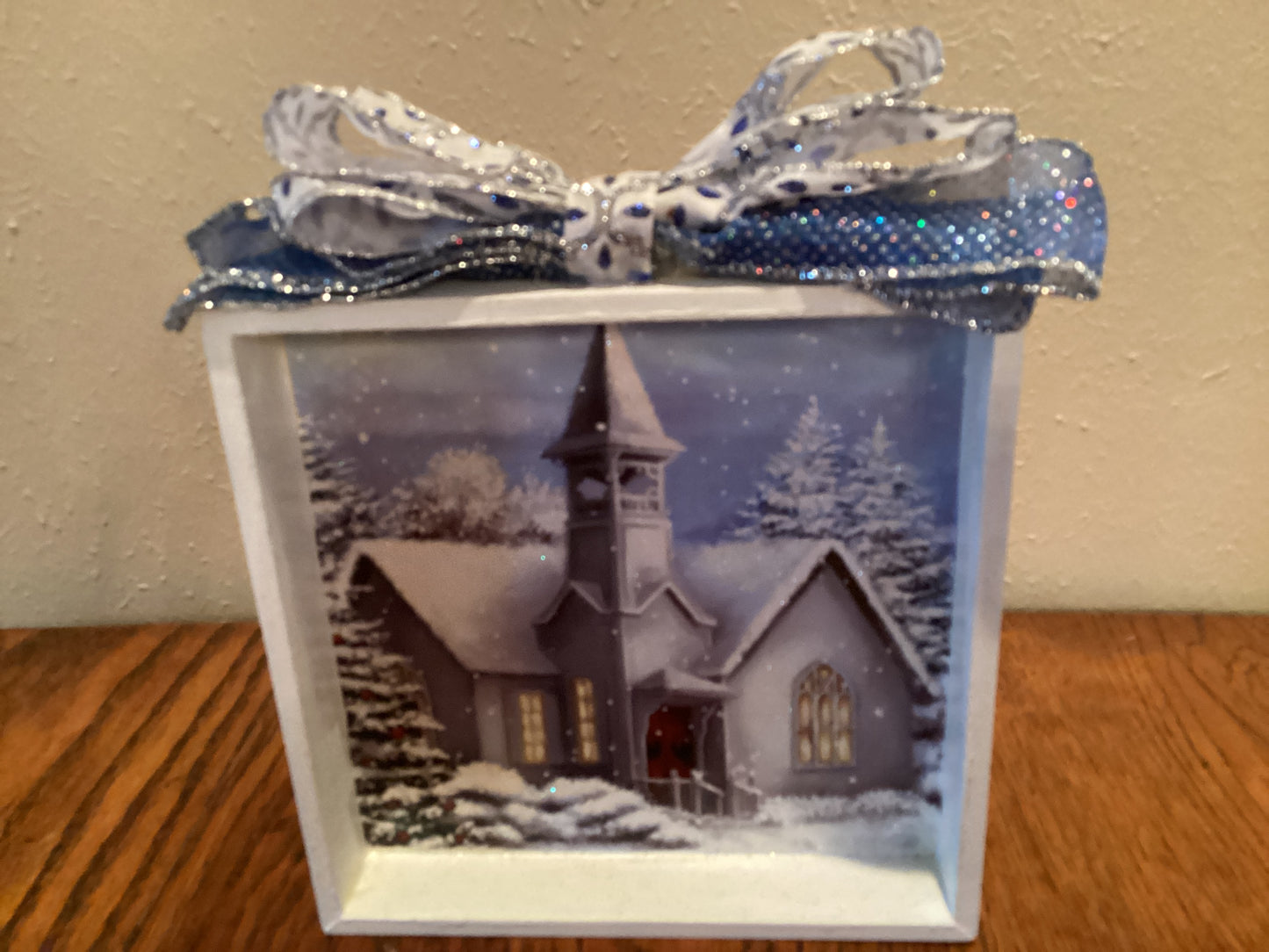 7" X 7" white box with snow-covered church and trees next to a Christmas tree on blue background