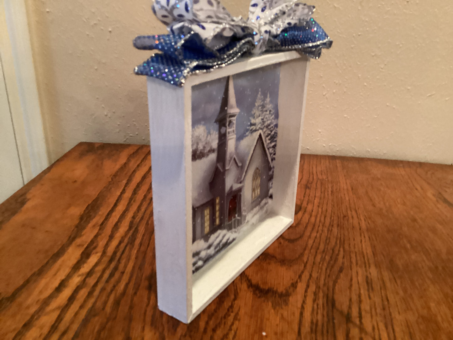 7" X 7" white box with snow-covered church and trees next to a Christmas tree on blue background